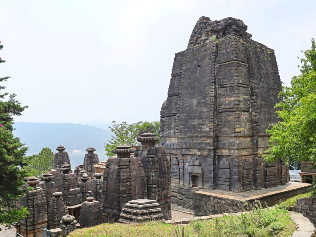 A cluster of ancient stone shrines at the Katarmal Sun Temple overlooking a valley.