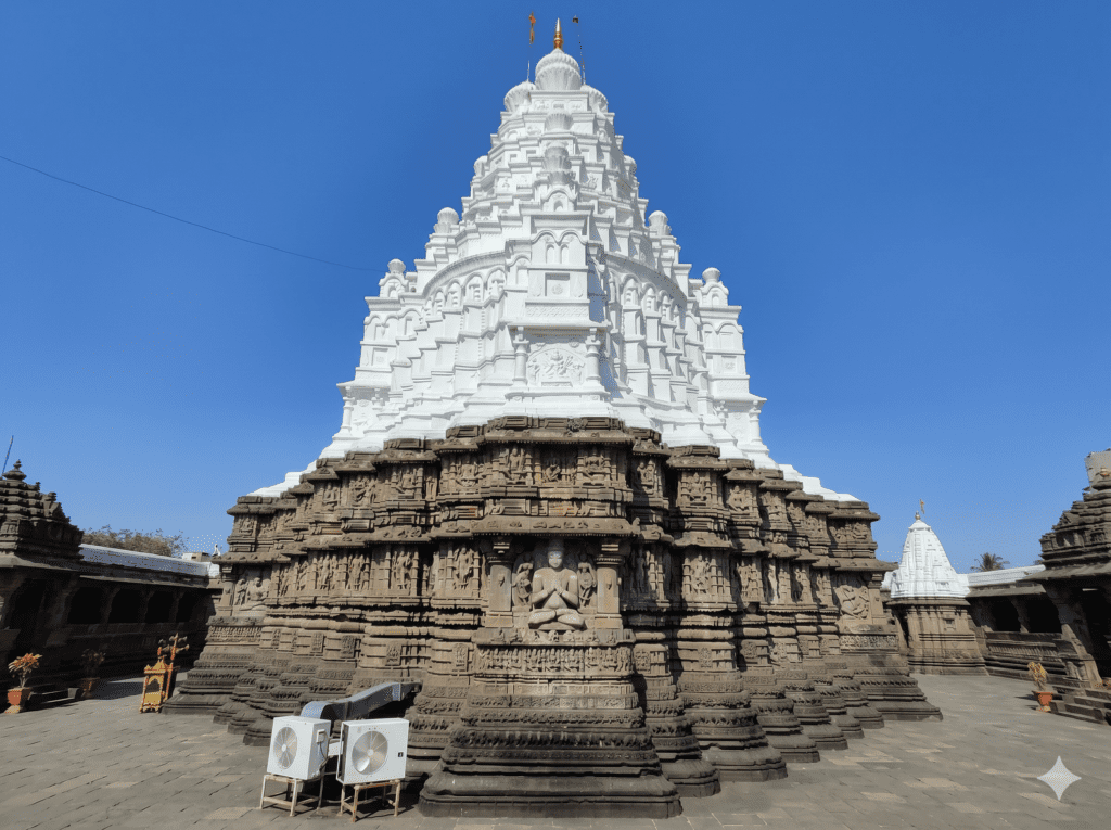 Exterior view of the Nageshwar Temple showing a large, carved stone base and white tiered tower