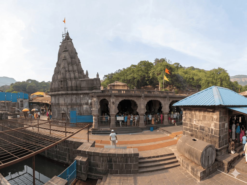 A wide-angle view of the stone Bhimashankar Temple complex with its prominent carved shikhara (spire) and devotees lined up under arched stone walkways