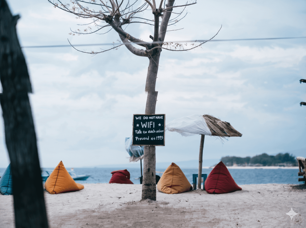 A wooden sign on a tree at the Island beach bar saying "We do not have WiFi, talk to each other."
