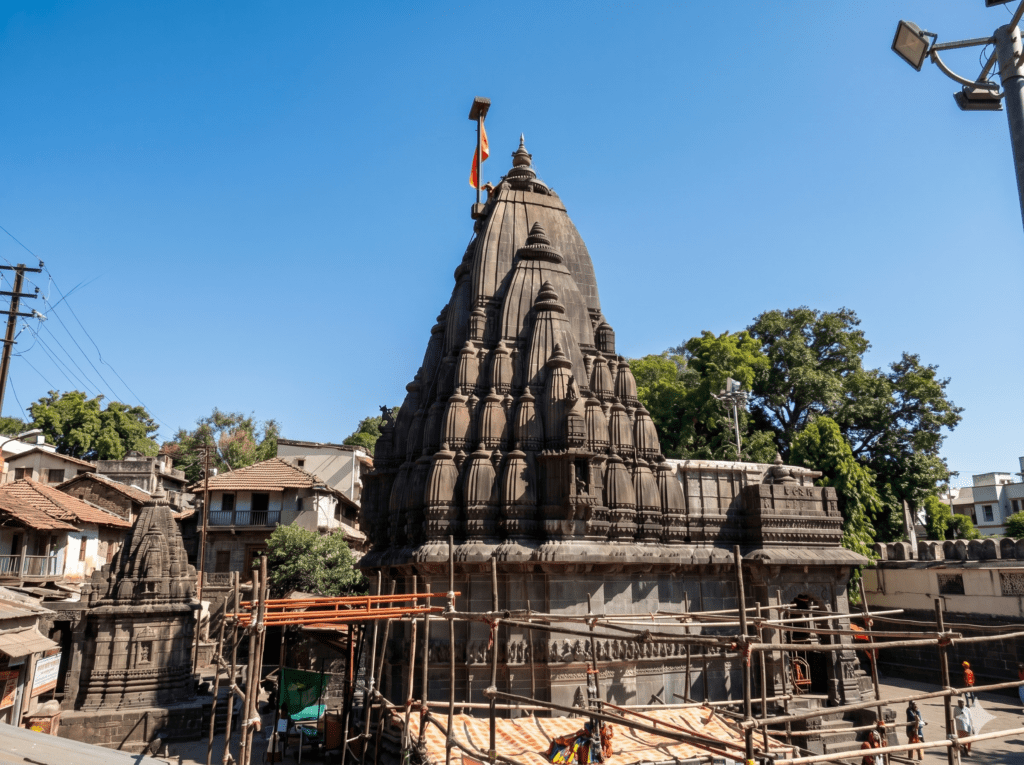 A wide shot of the stone Bhimashankar Temple spire in India, surrounded by scaffolding and older buildings