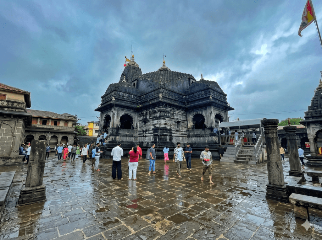 Wide shot of the dark stone and its wet, reflective courtyard filled with visitors under a cloudy sky