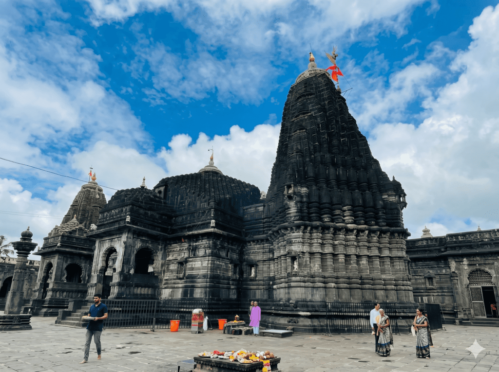 A majestic, dark stone ancient Hindu temple with intricate carvings and a tall spire under a blue sky