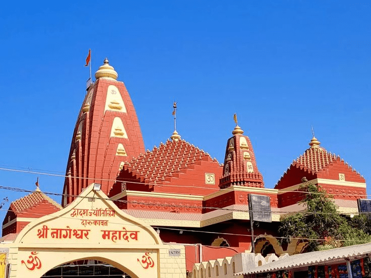 Exterior view of the red and gold Nageshwar Temple architecture under a bright blue sky.
