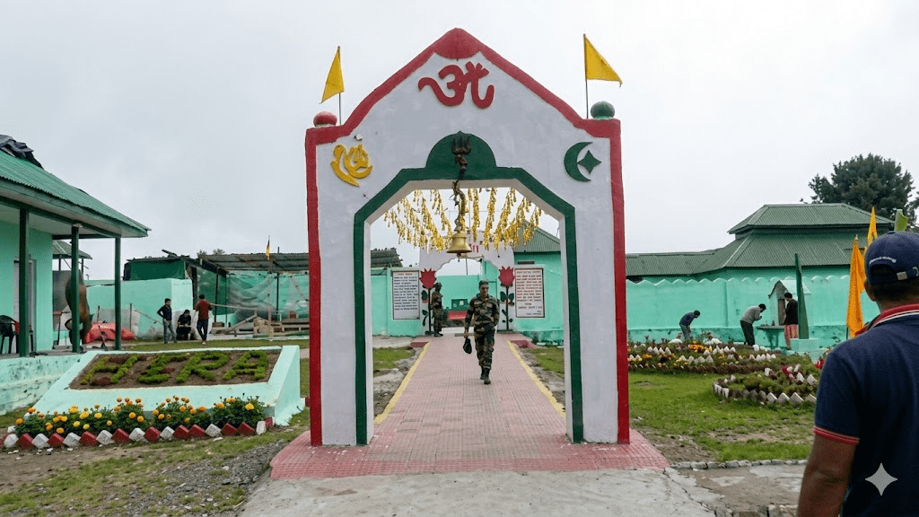 An arched entrance gate labeled "Sarv Dharma Sthal - All Religions Place" with various religious symbols, featuring a path leading inside where a soldier is walking.
