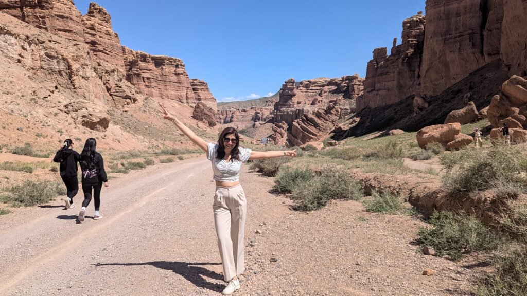 A smiling tour leader with arms extended in the Canyon.